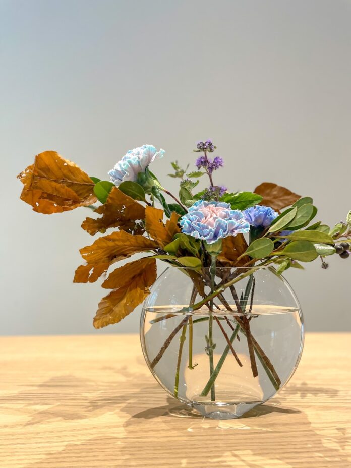 Photo by oning a glass vase filled with flowers on top of a wooden table