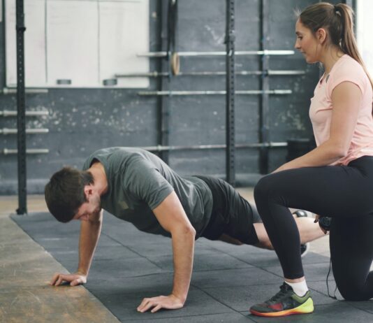 집에서도 쉽게 시작하는 근육 건강, 일상 속 탄탄한 습관이 열쇠 Man doing push-ups with a trainer spotting him.