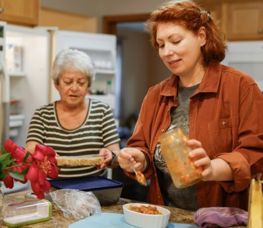 생활 속 니트(NEAT) 다이어트: 헬스장 밖에서도 칼로리를 태우는 일상 활동의 위력 Two women preparing food in a kitchen.
