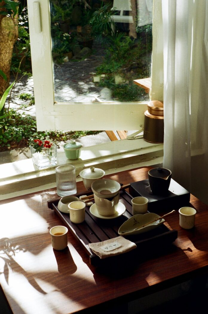 Photo by Khanh Do Tea set arranged on a wooden tray by the window.