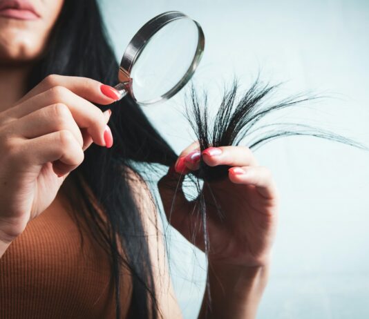 변화하는 헤어 건강 트렌드… 집에서 실천하는 두피 케어 루틴이 인기 Woman examining split ends of hair with magnifying glass