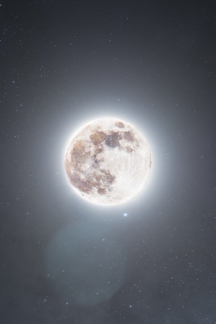 A glowing full moon in a dark, starry night sky.