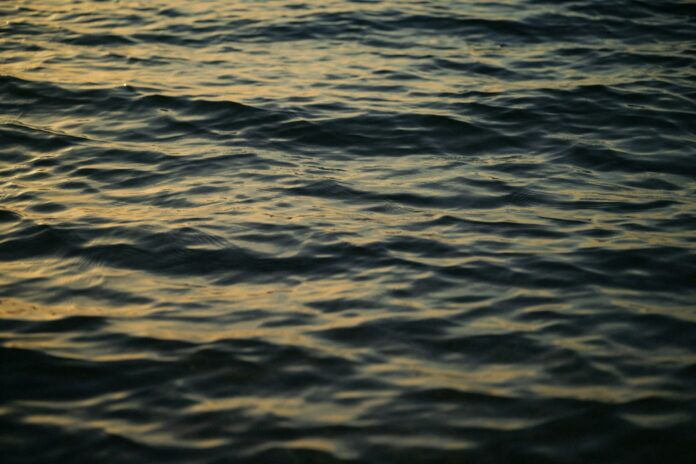 Photo by Emanuel Haas Rippling dark water reflecting golden hour light